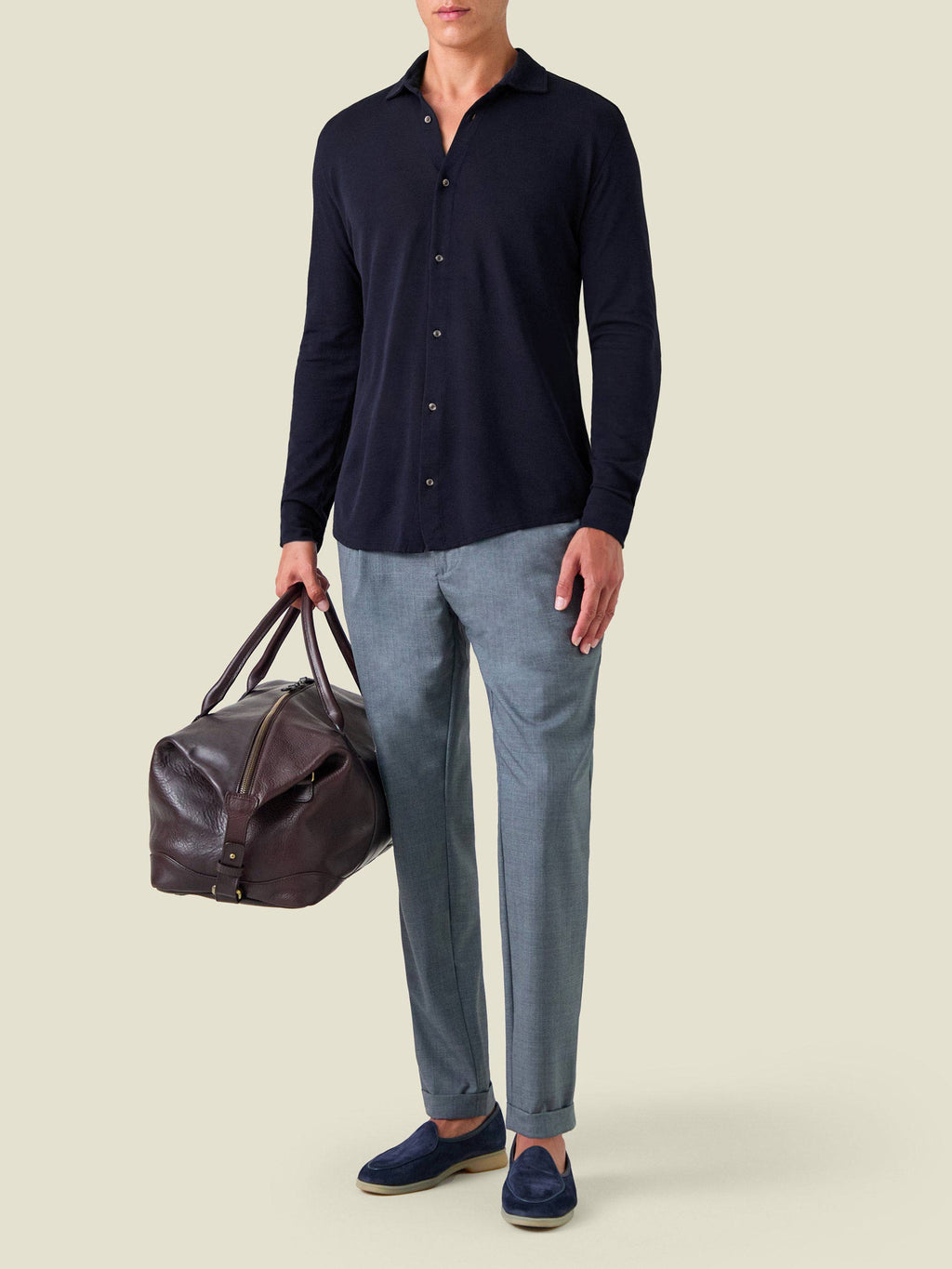 Model wears the Silk-Cotton Piqué Shirt in Midnight Blue, styled with light blue trousers and a brown leather bag.