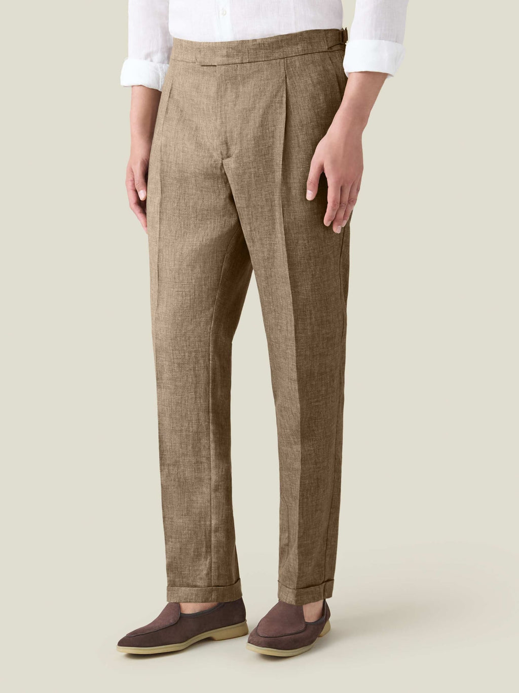 Model wearing Luca Faloni's Hazelnut Brown Linen Elegant Trousers with a white shirt and brown loafers, shown side-on.
