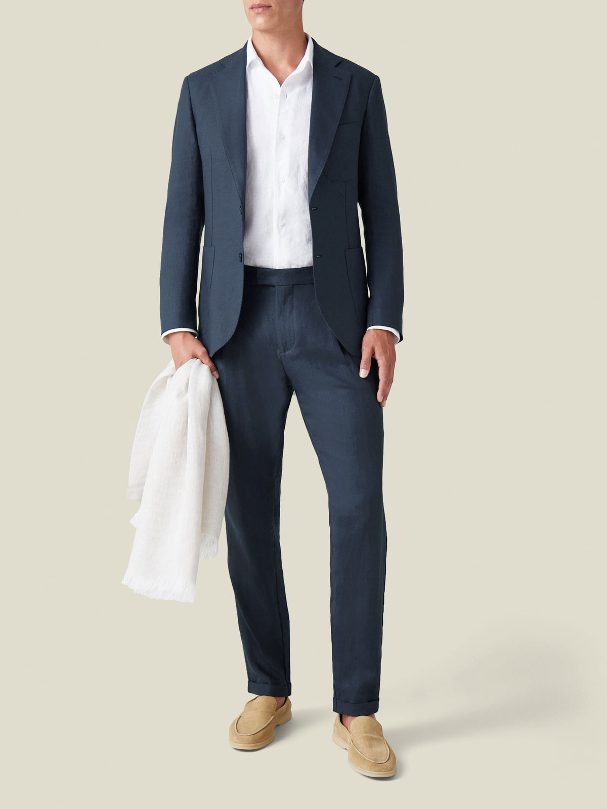 A model wears the Luca Faloni Linen Suit in Navy Blue, styled with a white shirt and tan loafers.