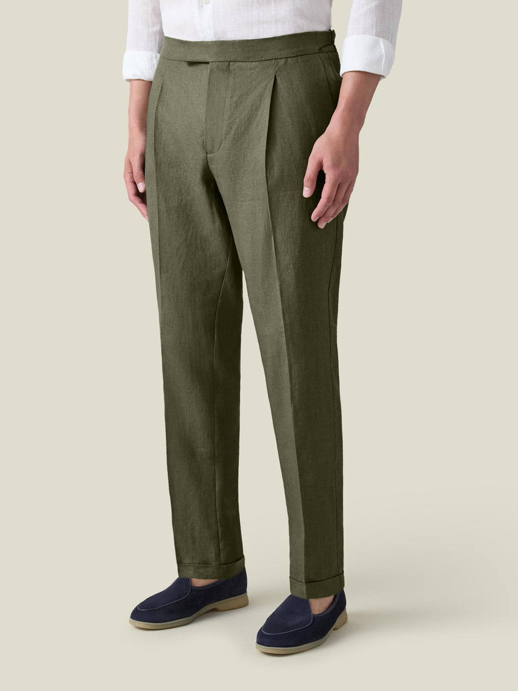 A model wears Luca Faloni's olive green Linen Elegant Trousers, styled with a white shirt and navy loafers.