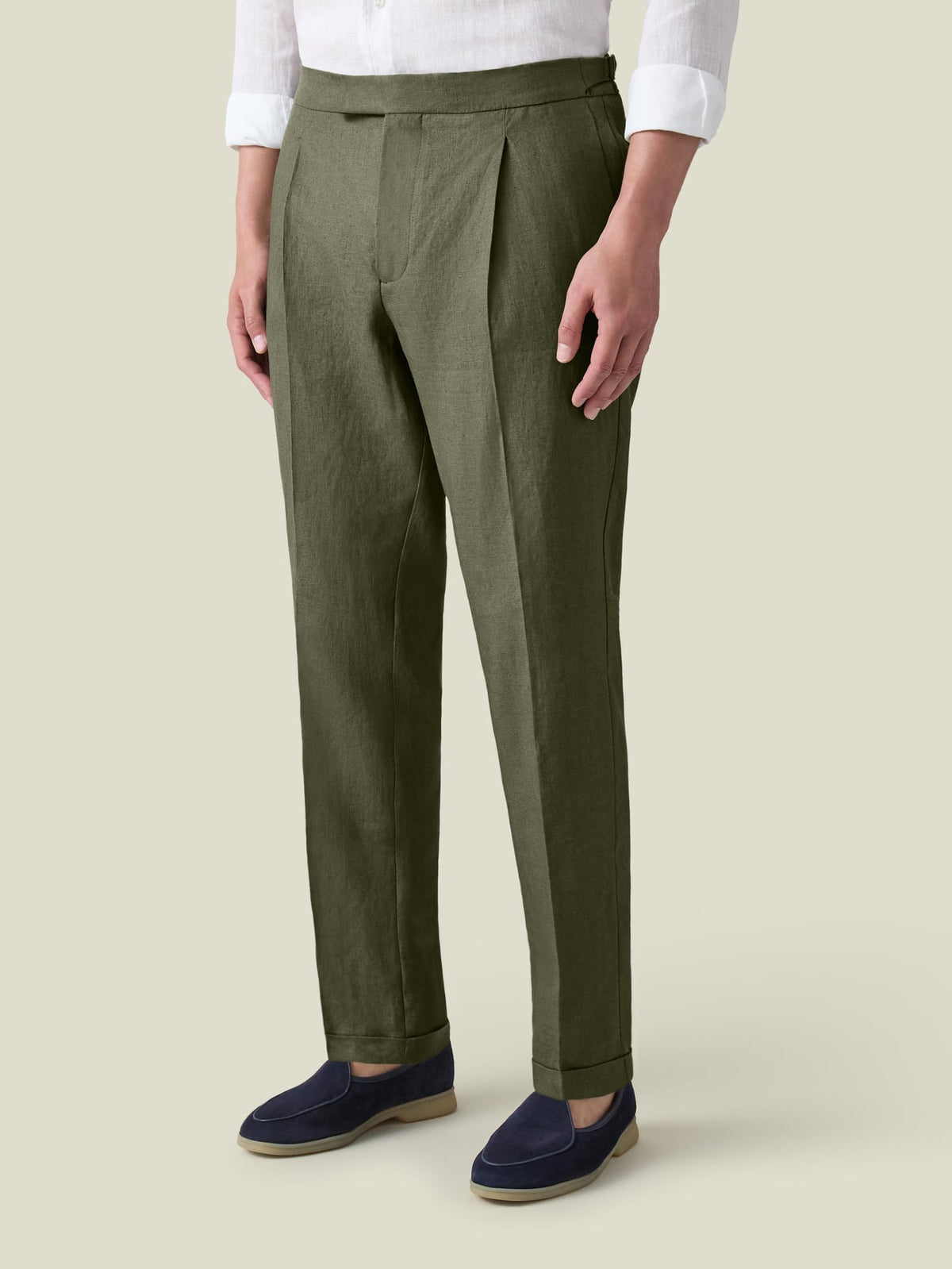 A model wears Luca Faloni's olive green Linen Elegant Trousers, styled with a white shirt and navy loafers.