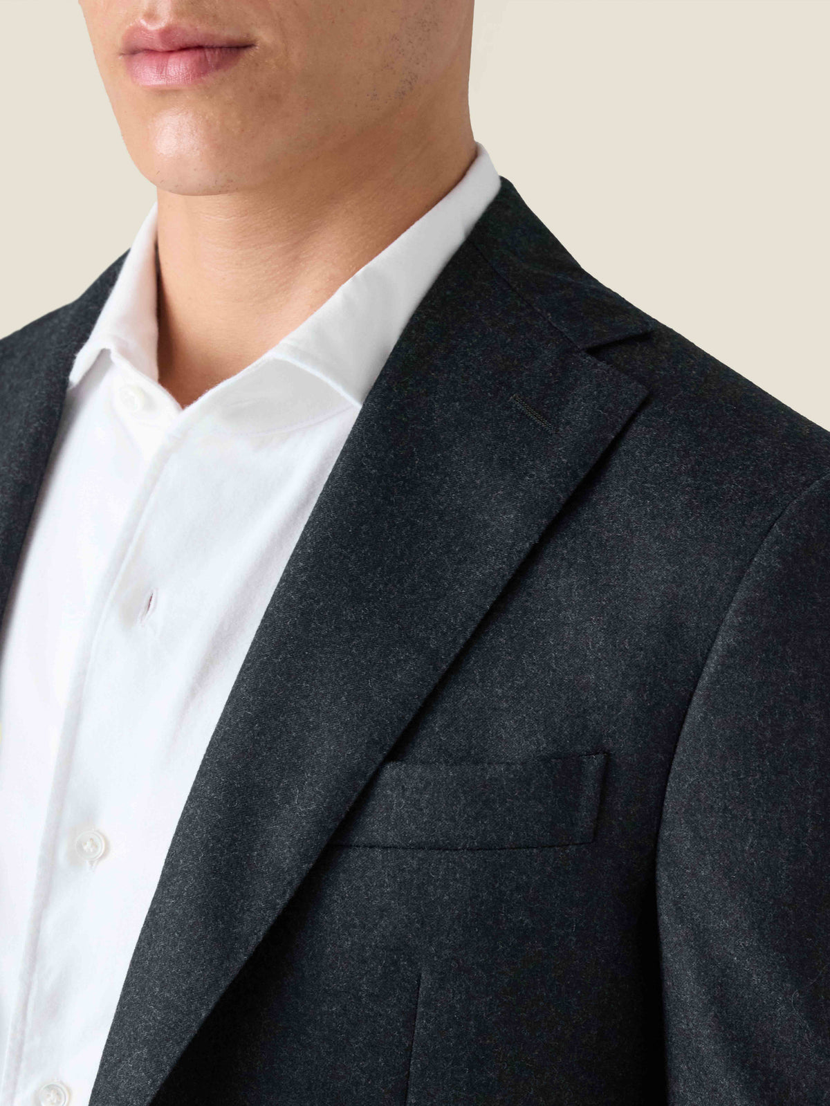 A close-up of the Charcoal Grey Wool Blazer, highlighting its notch lapel, welt chest pocket, and soft brushed wool texture.