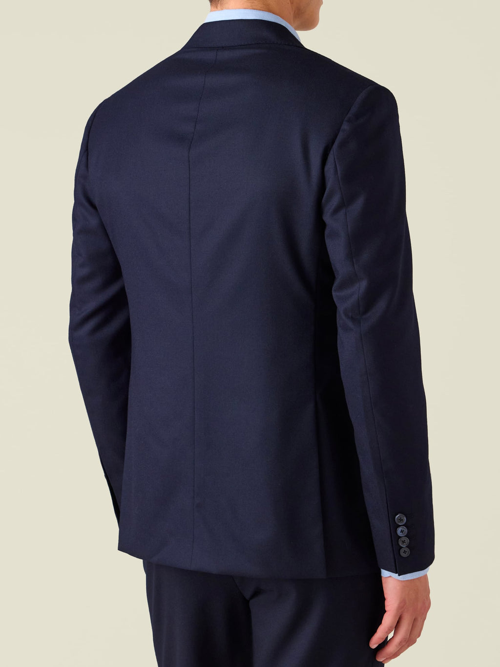 Back view of a model wearing the Midnight Blue Wool Blazer, showcasing its tailored fit, centre seam, and surgeon's cuff.