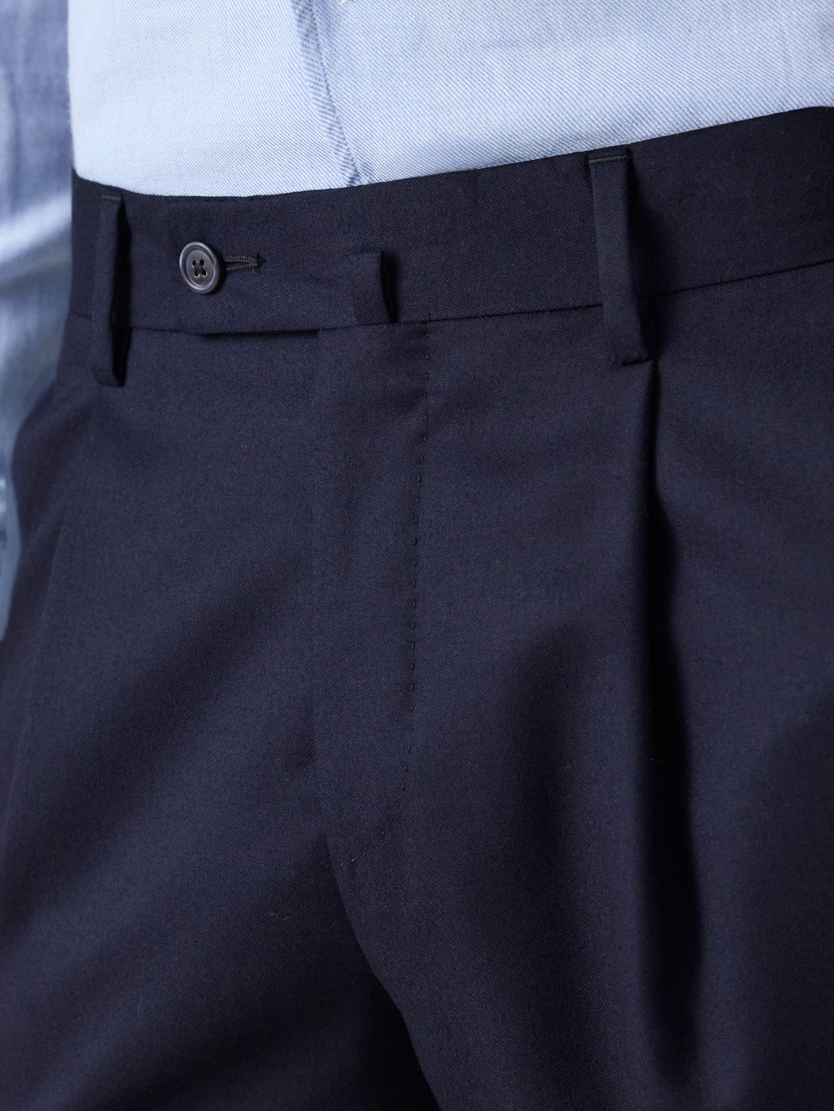 A close-up view of the front of the Classic Wool Trousers in midnight blue, highlighting the single pleat and waistband.