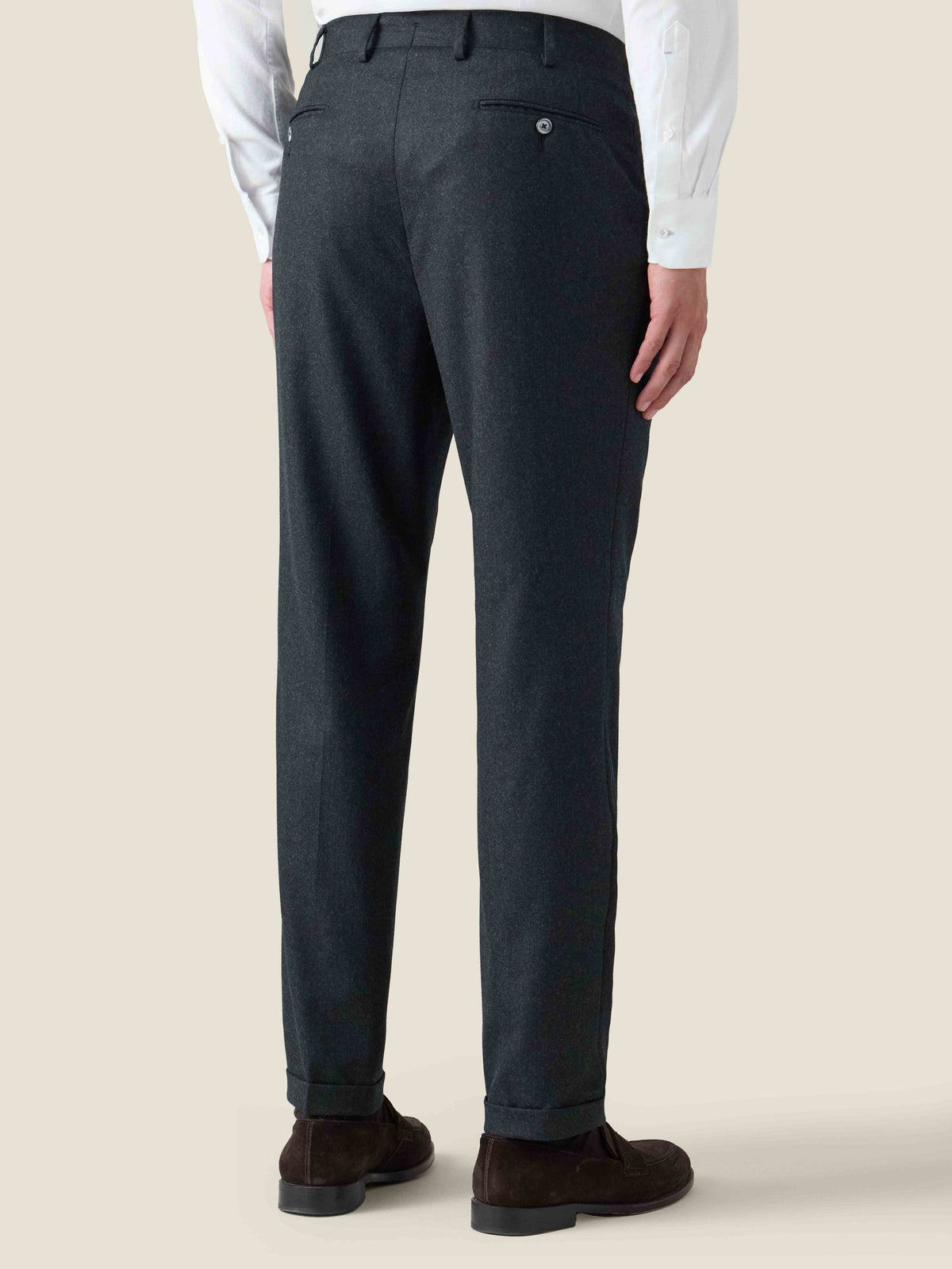 Back view of a model wearing Luca Faloni's charcoal grey Classic Wool Trousers with cuffed hems and a back pocket.