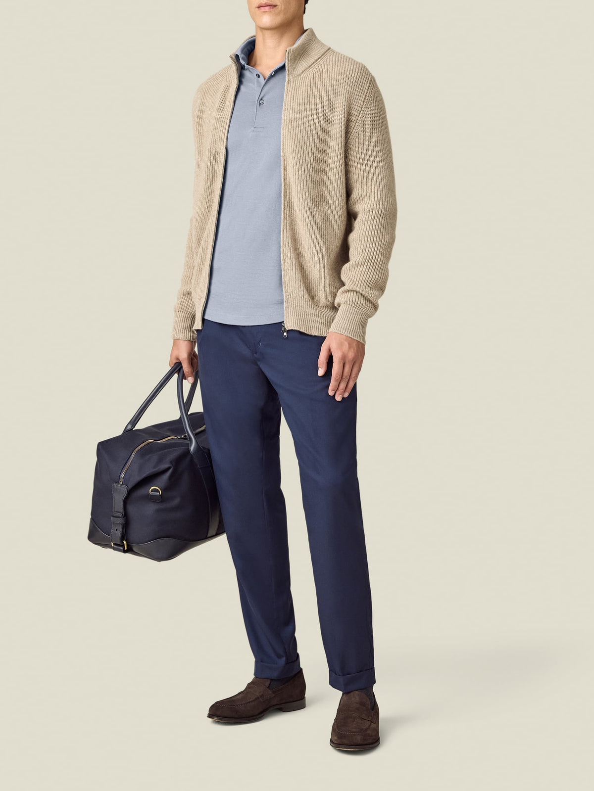 A model wears the French Blue Cashmere-Cotton Polo, layered under a beige zip cardigan and paired with navy trousers.