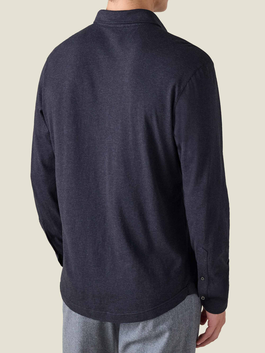 Back view of a man in a Midnight Blue Cashmere-Cotton Polo, showing the relaxed fit, shirt cuffs, and rounded hem.