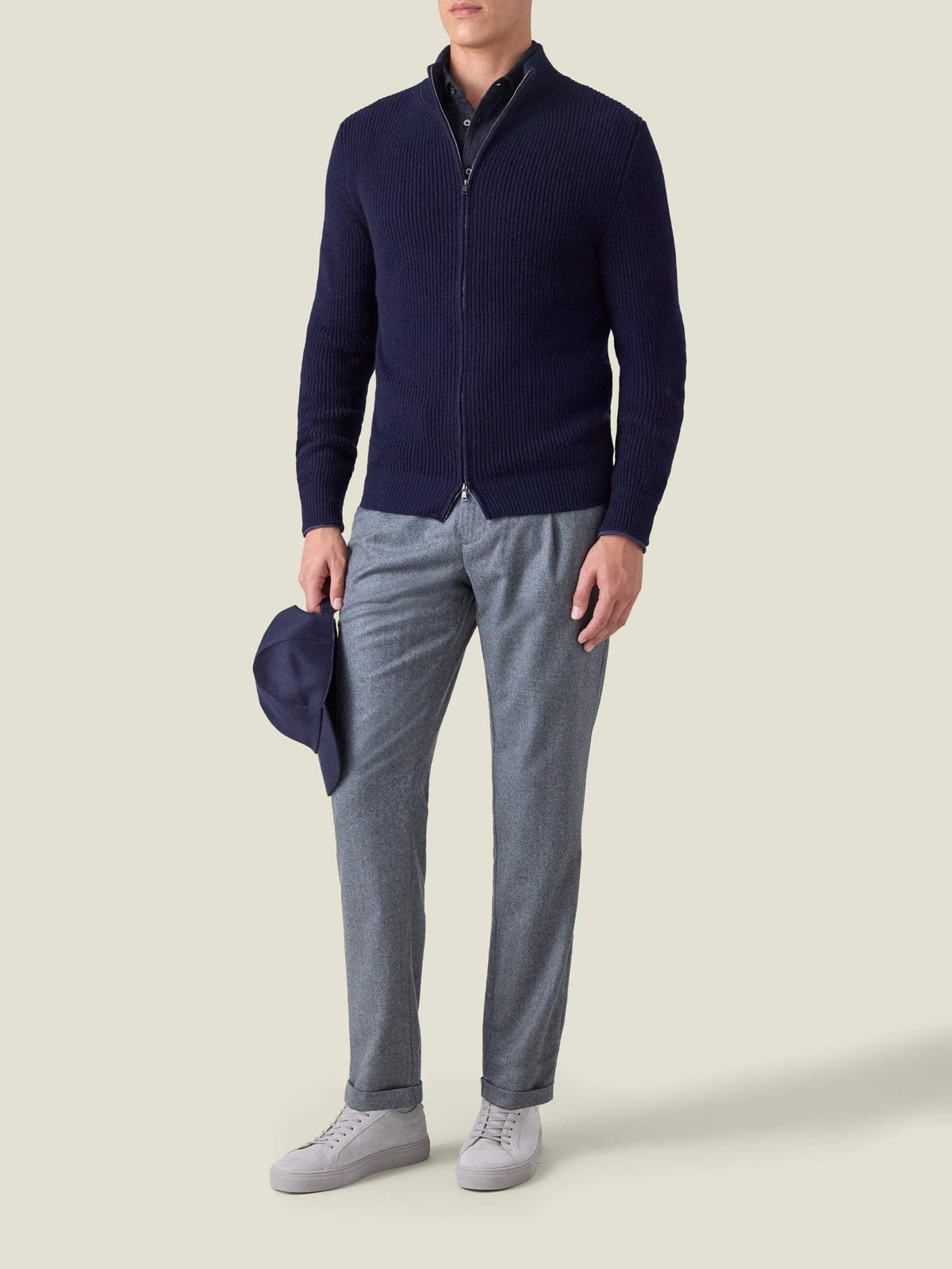 A model wears the Midnight Blue Cashmere-Cotton Polo Shirt, layered under a navy zip cardigan and paired with grey trousers.
