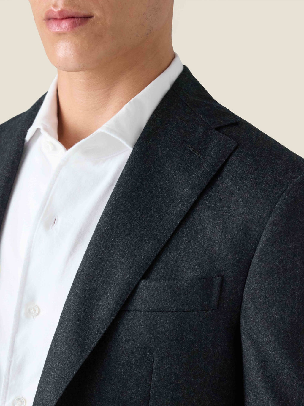 Close-up of a man wearing the Charcoal Grey Wool Suit, detailing the notch lapel, shoulder, and brushed virgin wool fabric.