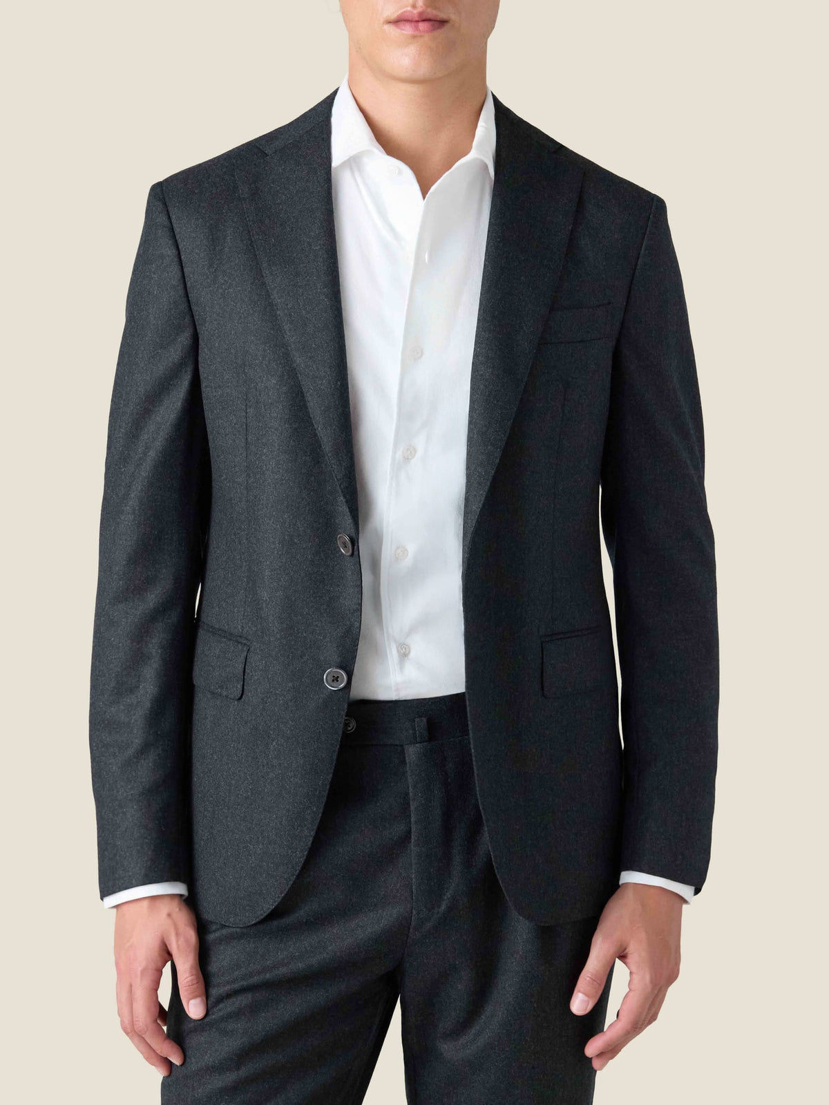 A front view of a model wearing the Charcoal Grey Wool Suit, paired with a white collared shirt.