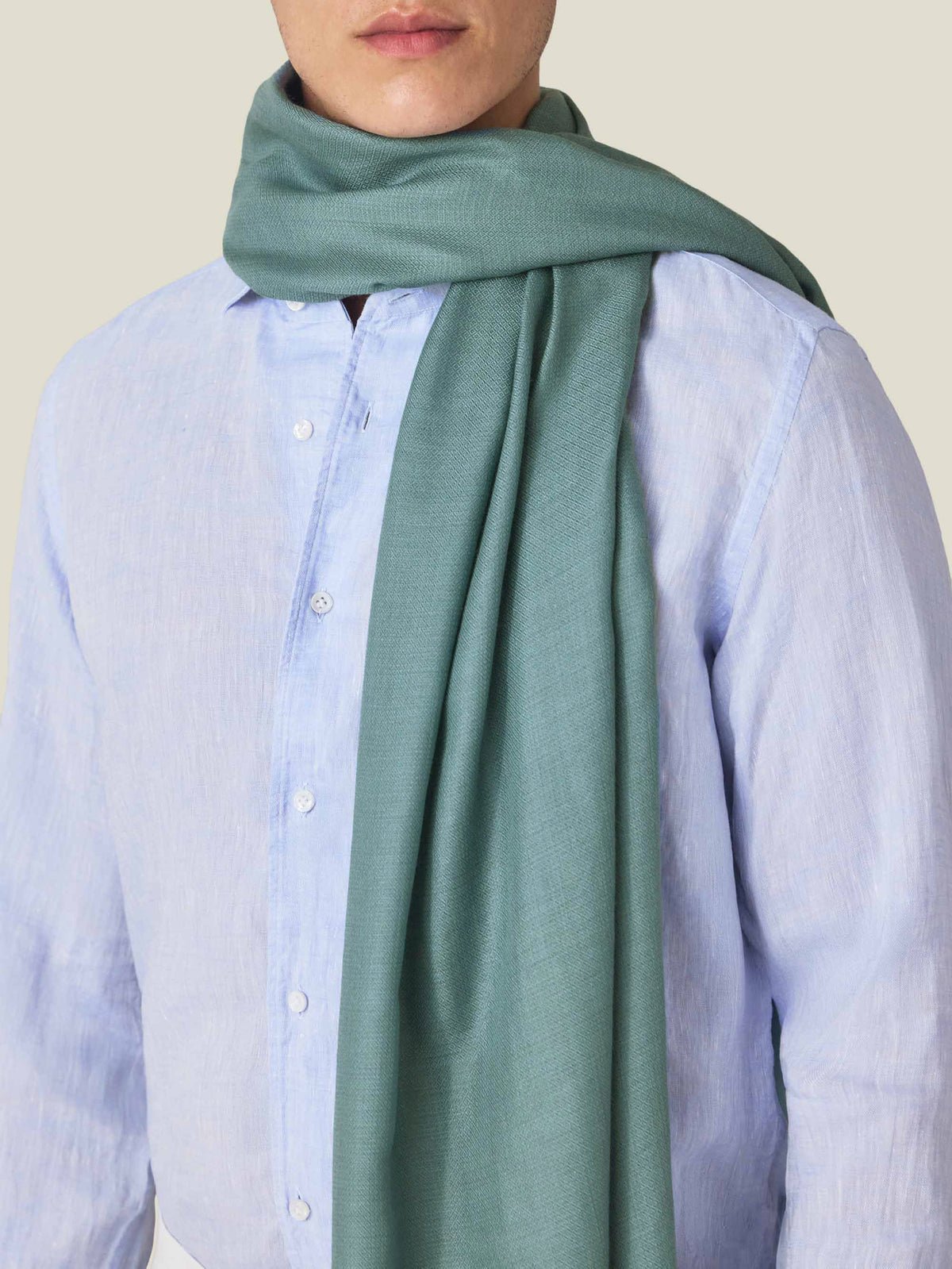 A close-up of a model wearing the Teal Silk-Cashmere Scarf over a light blue shirt, highlighting its soft, fine texture.