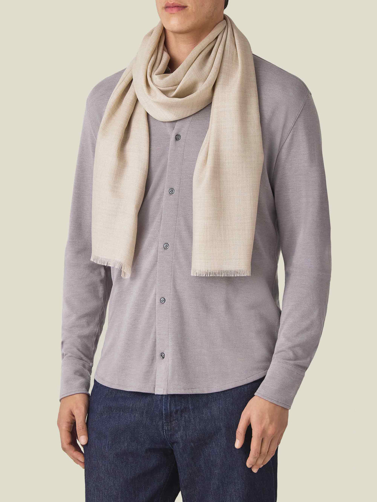 Front view of a model wearing the Sand Silk-Cashmere Scarf over a grey long-sleeve shirt and dark jeans.