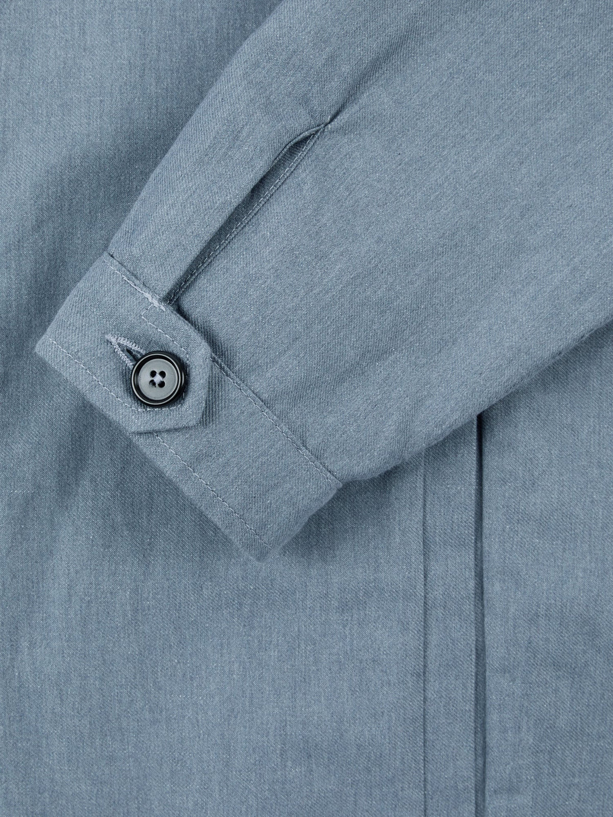 Detail of the single horn button cuff on the French Blue Linen-Cotton Bomber Jacket, showcasing the fabric texture.