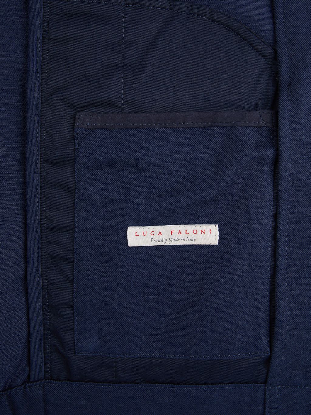 A close-up of the 'Luca Faloni, Proudly Made in Italy' label on the inner pocket of the Midnight Blue Linen Bomber Jacket.