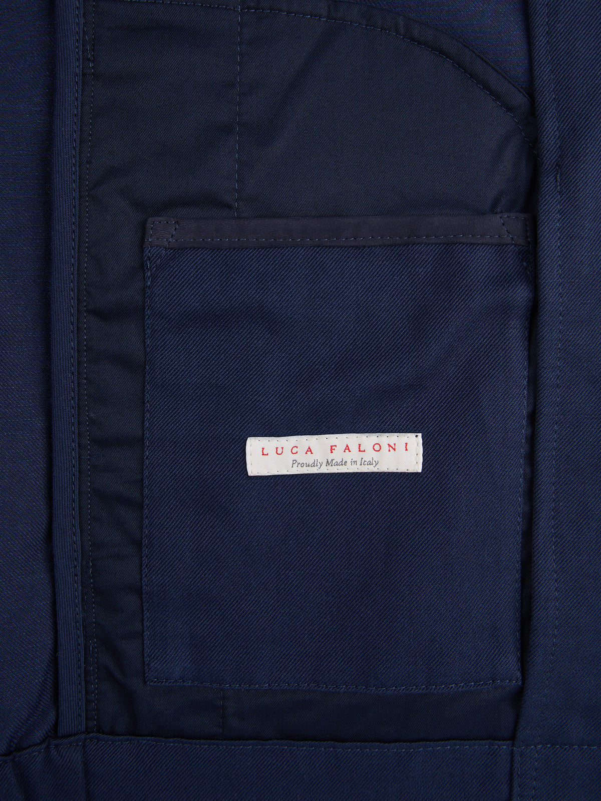 A close-up of the 'Luca Faloni, Proudly Made in Italy' label on the inner pocket of the Midnight Blue Linen Bomber Jacket.