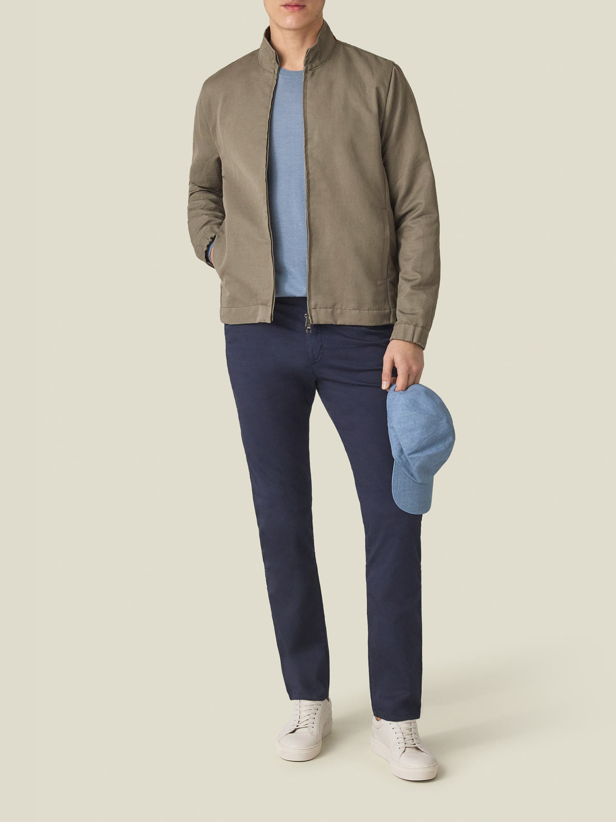 Model wearing the Luca Faloni Linen Bomber Jacket in Nocciola Brown, paired with a blue t-shirt and navy trousers.