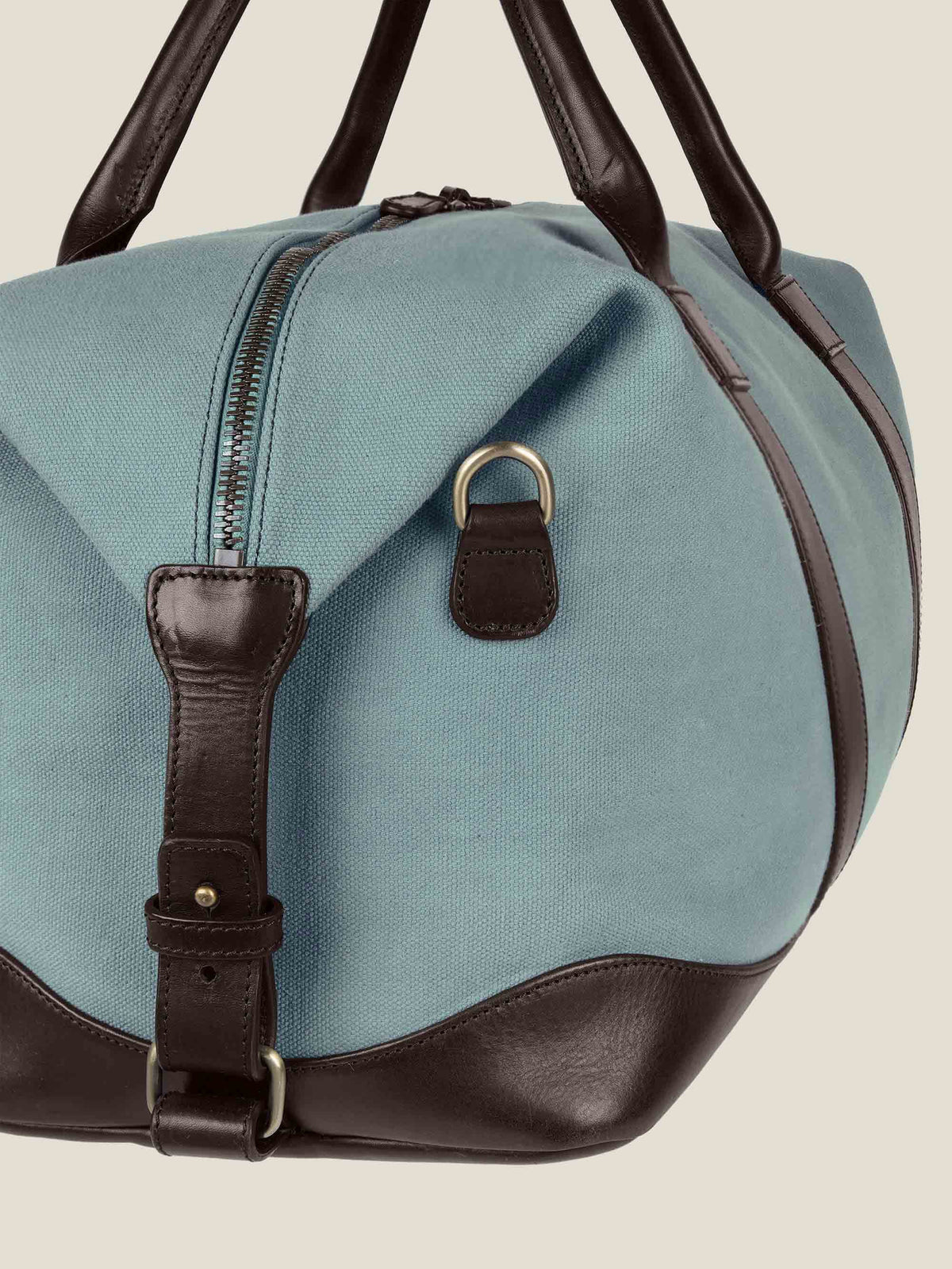 Detailed side view of the French Blue Canvas Bag, showing the dark brown leather handles, side adjuster, and zip closure.
