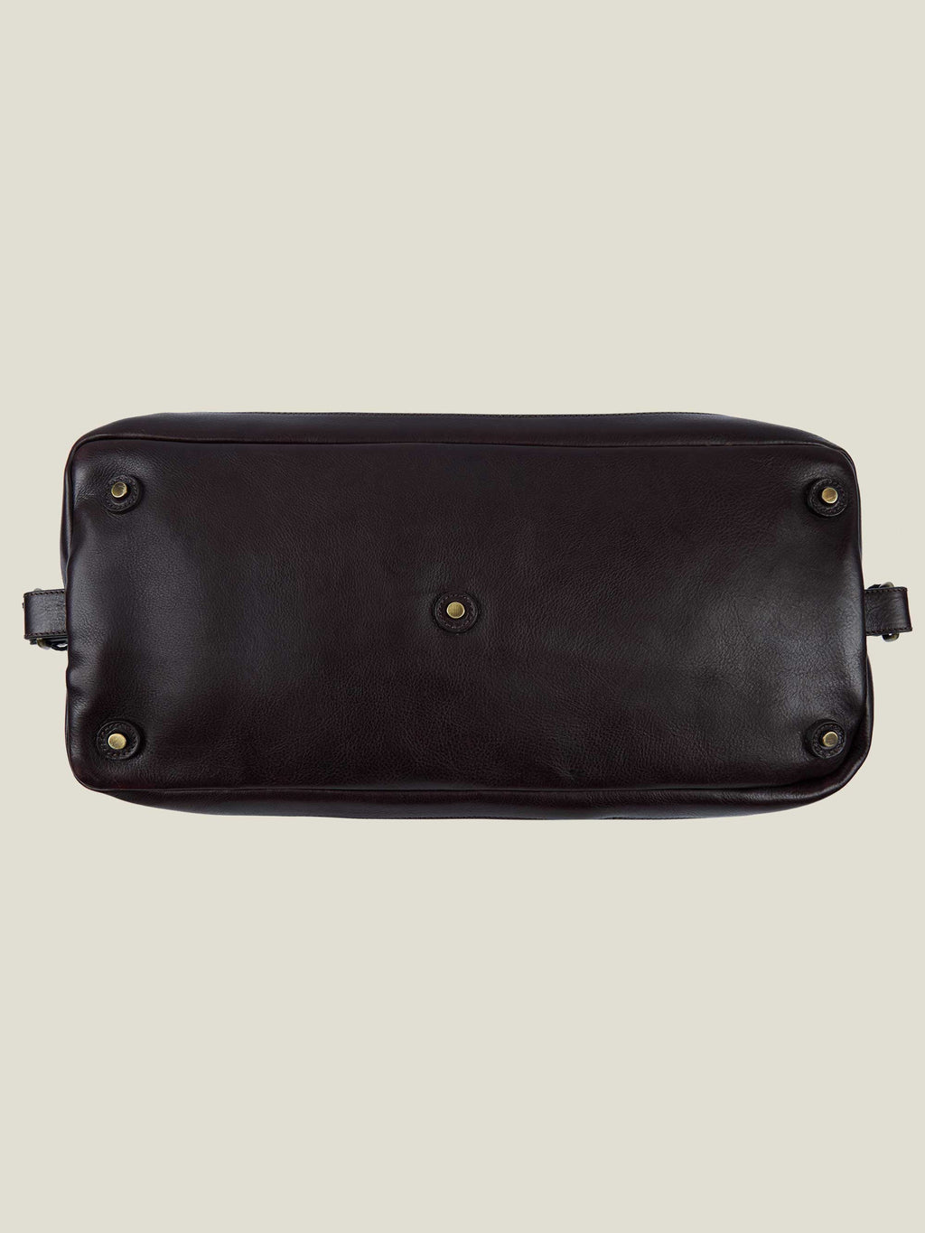 Bottom view of the Sand Canvas Bag, showing the dark brown leather base with five protective metal studs for durability.