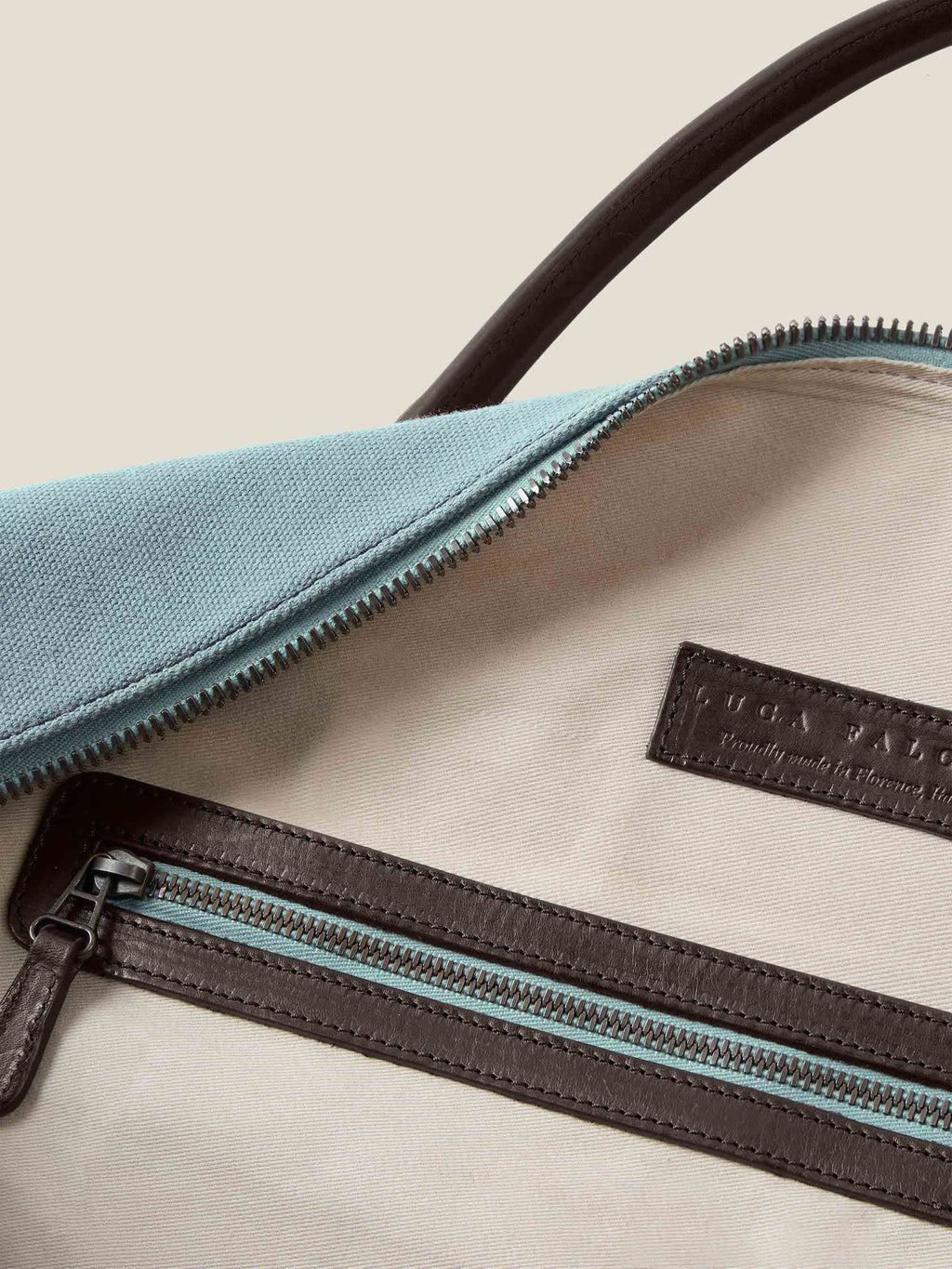 Interior detail of the French Blue Canvas Bag with its natural canvas lining, leather-trimmed zip pocket and brand logo.
