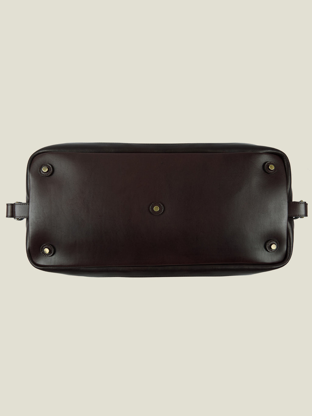 Detail of the underside of the Caramel Brown Canvas Bag, showing the protective leather base and metal studs.