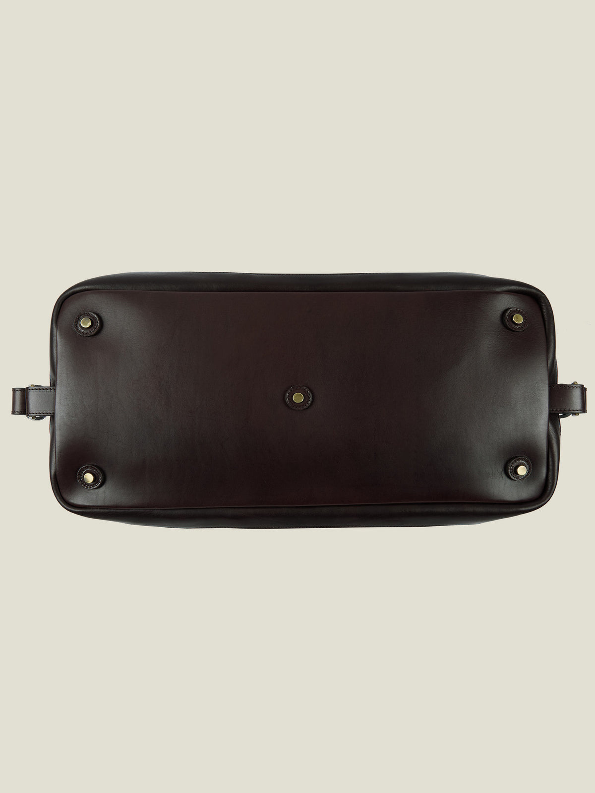 Detail of the underside of the Caramel Brown Canvas Bag, showing the protective leather base and metal studs.