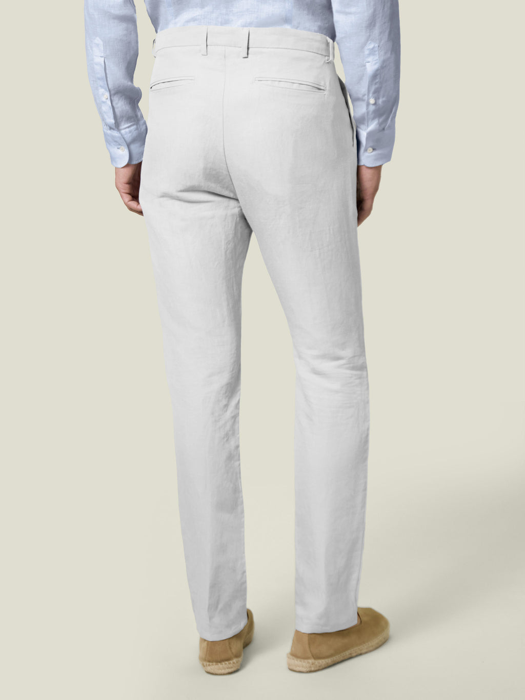 Model seen from the back wearing Luca Faloni's White Linen Cotton Trousers, paired with a light blue shirt.