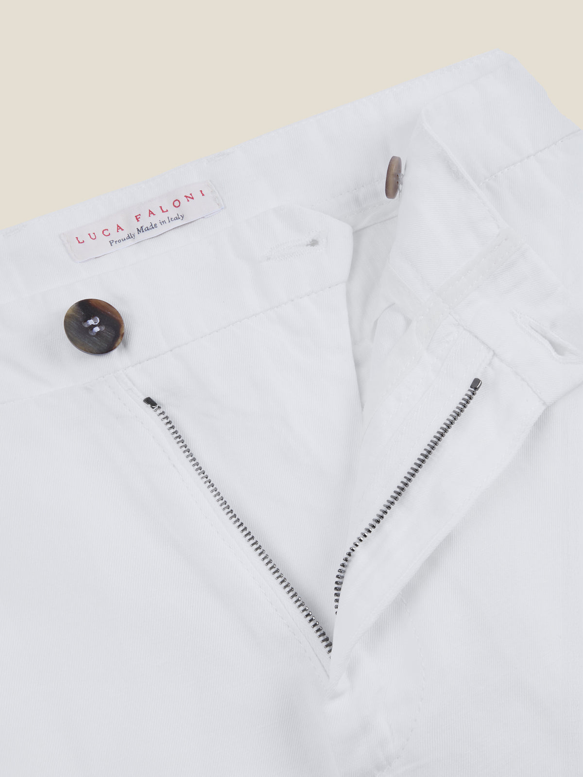 Close-up of the zip fly and double horn buttons on Luca Faloni's White Linen Cotton Trousers, showing the inner label.