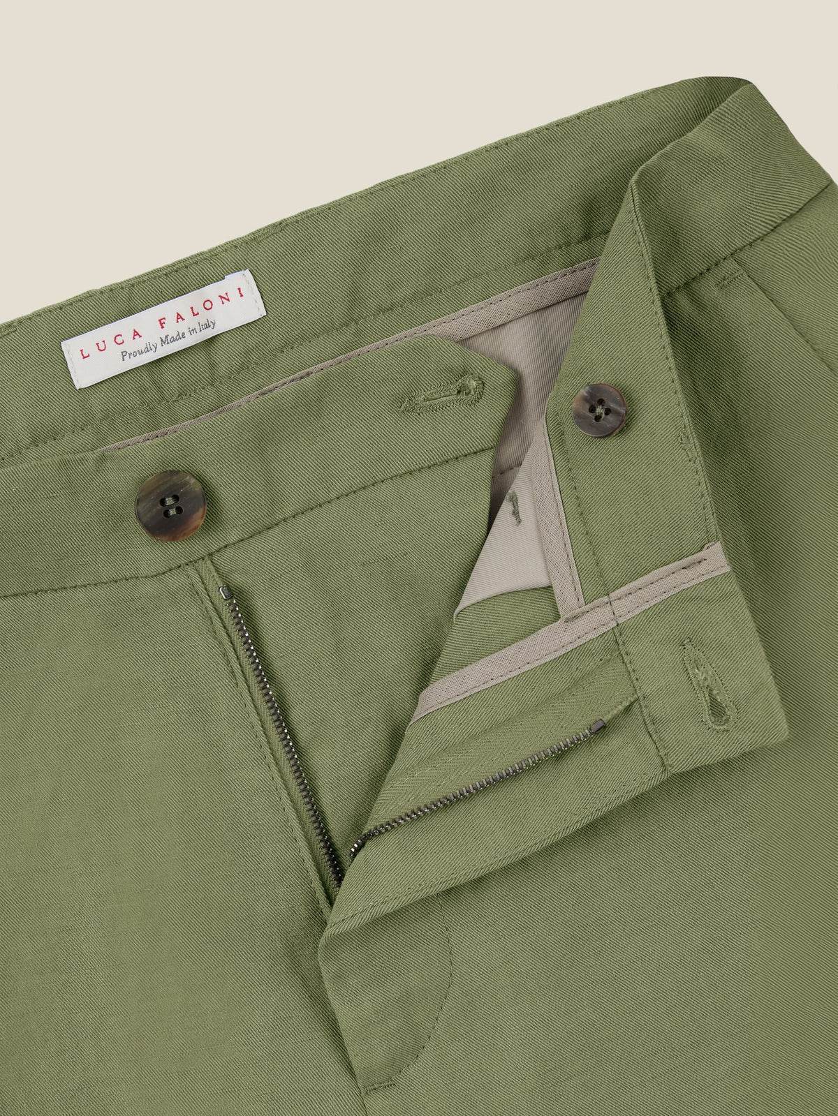 Close-up of Luca Faloni's Sage Green Linen Cotton Trousers, showing the horn button closure, zip fly and waistband detail.