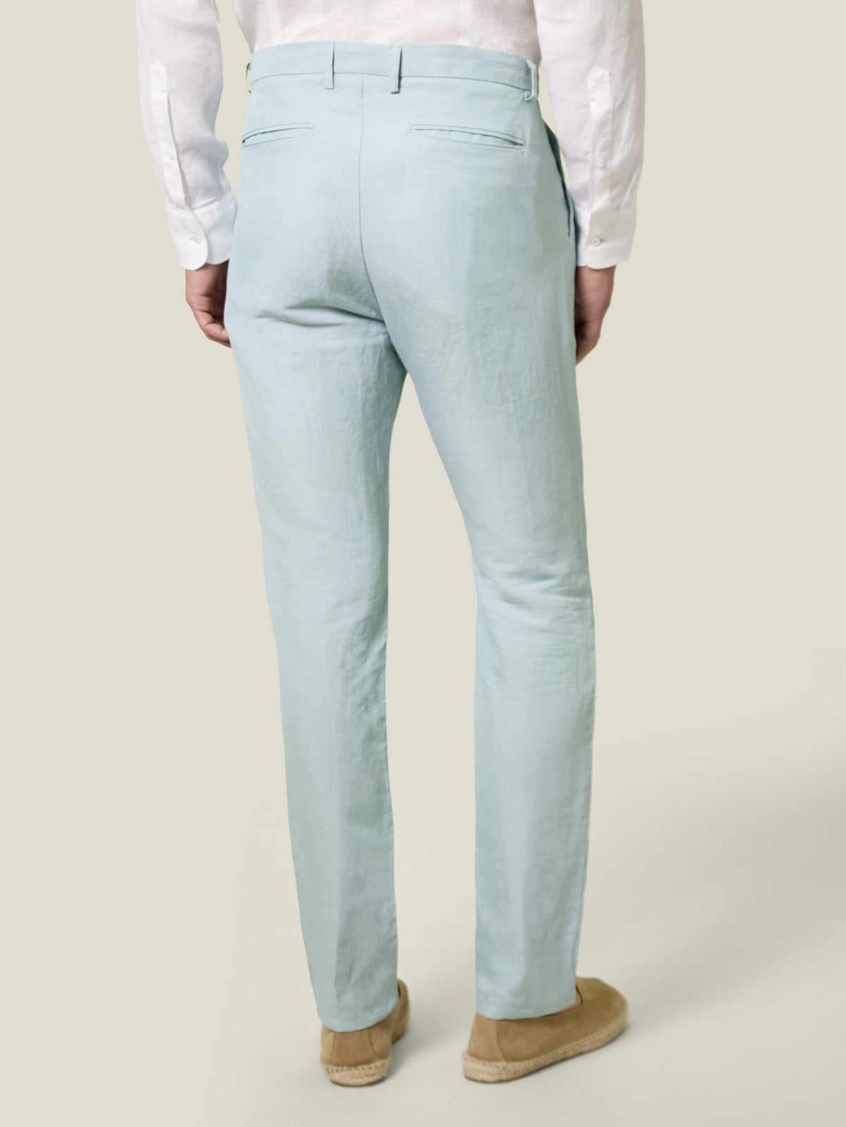 A model seen from the back wearing the Light Blue Linen Cotton Trousers by Luca Faloni with a white shirt.