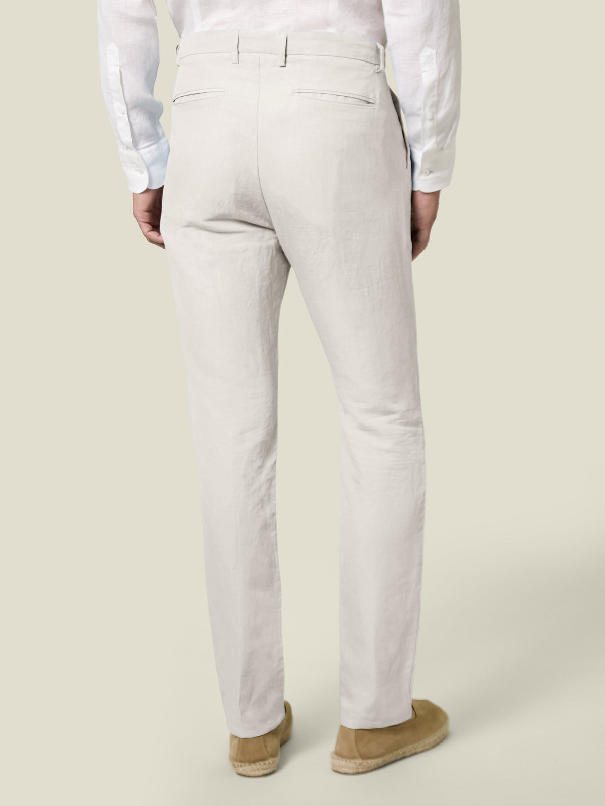 Back view of a model wearing Luca Faloni's Sand Linen-Cotton Trousers, showcasing the tapered fit and back pocket details.