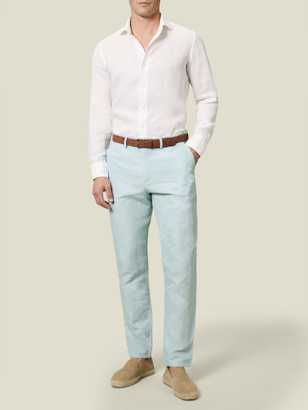 A model stands facing forward wearing the light blue Linen Cotton Trousers with a white shirt, brown belt, and espadrilles.
