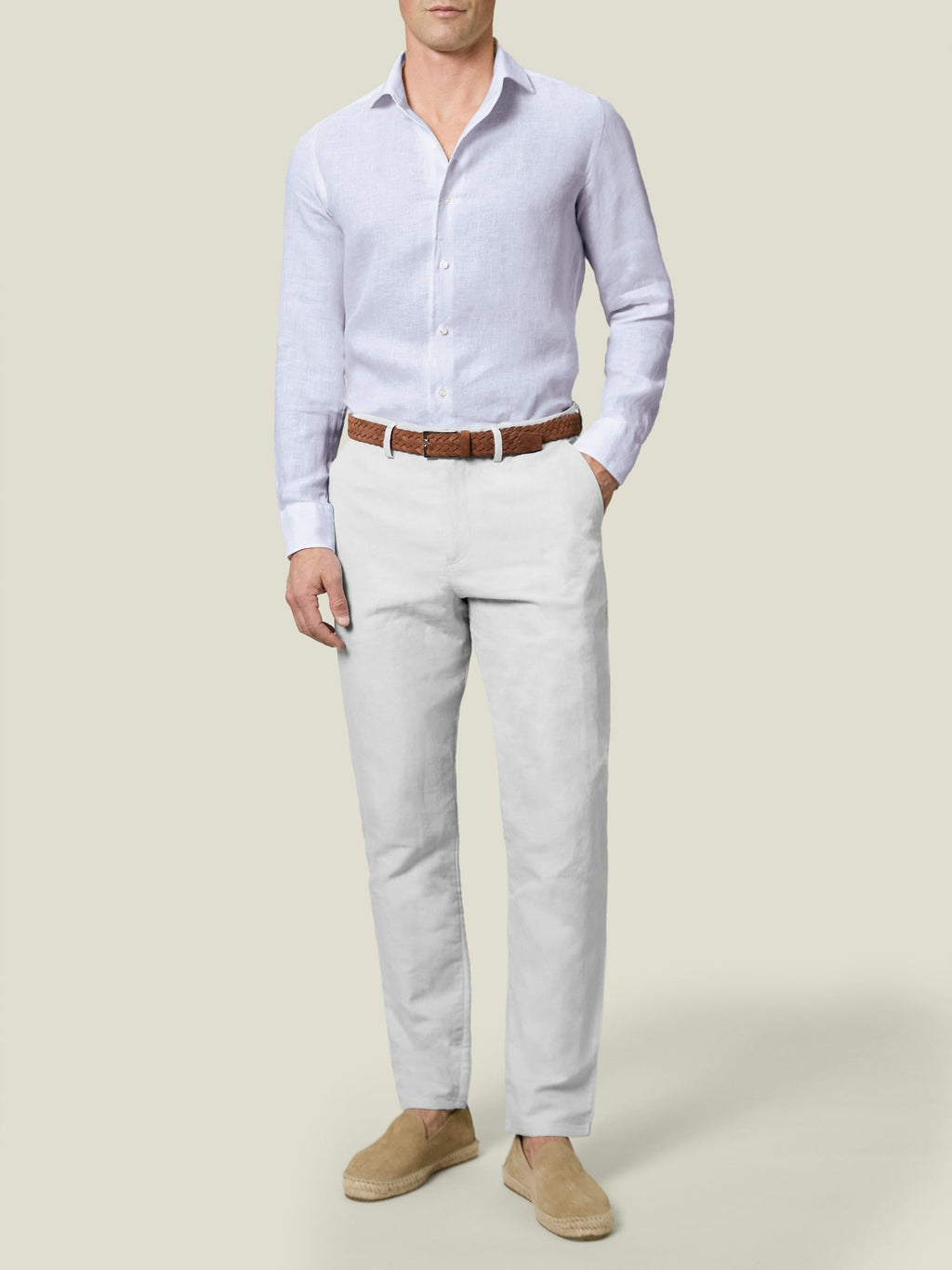 Front view of a man wearing white linen-cotton trousers with a light blue long-sleeve shirt and a brown woven belt.