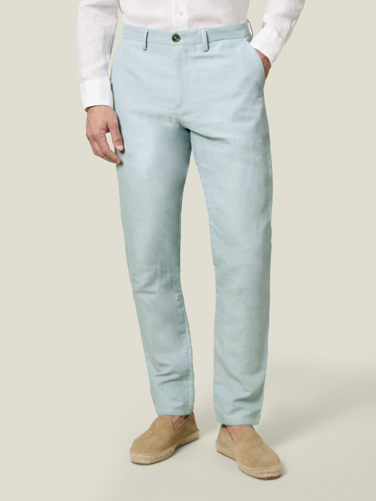 Front view of a model wearing light blue linen-cotton trousers with a white shirt and tan espadrilles.