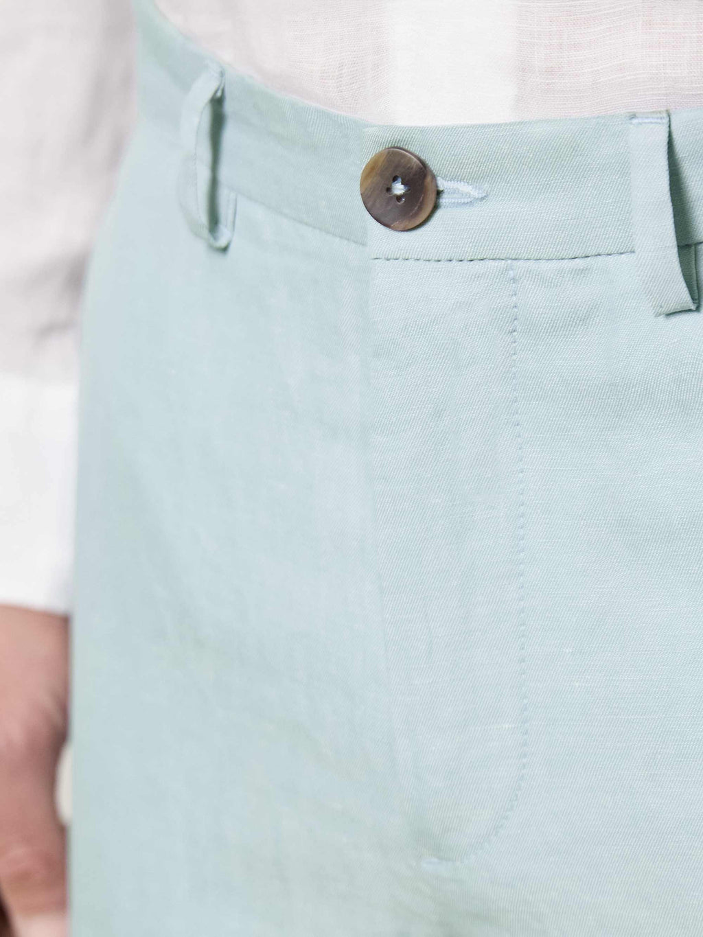 Close-up of the Light Blue Linen Cotton Trousers, detailing the horn button, waistband, and fine fabric.