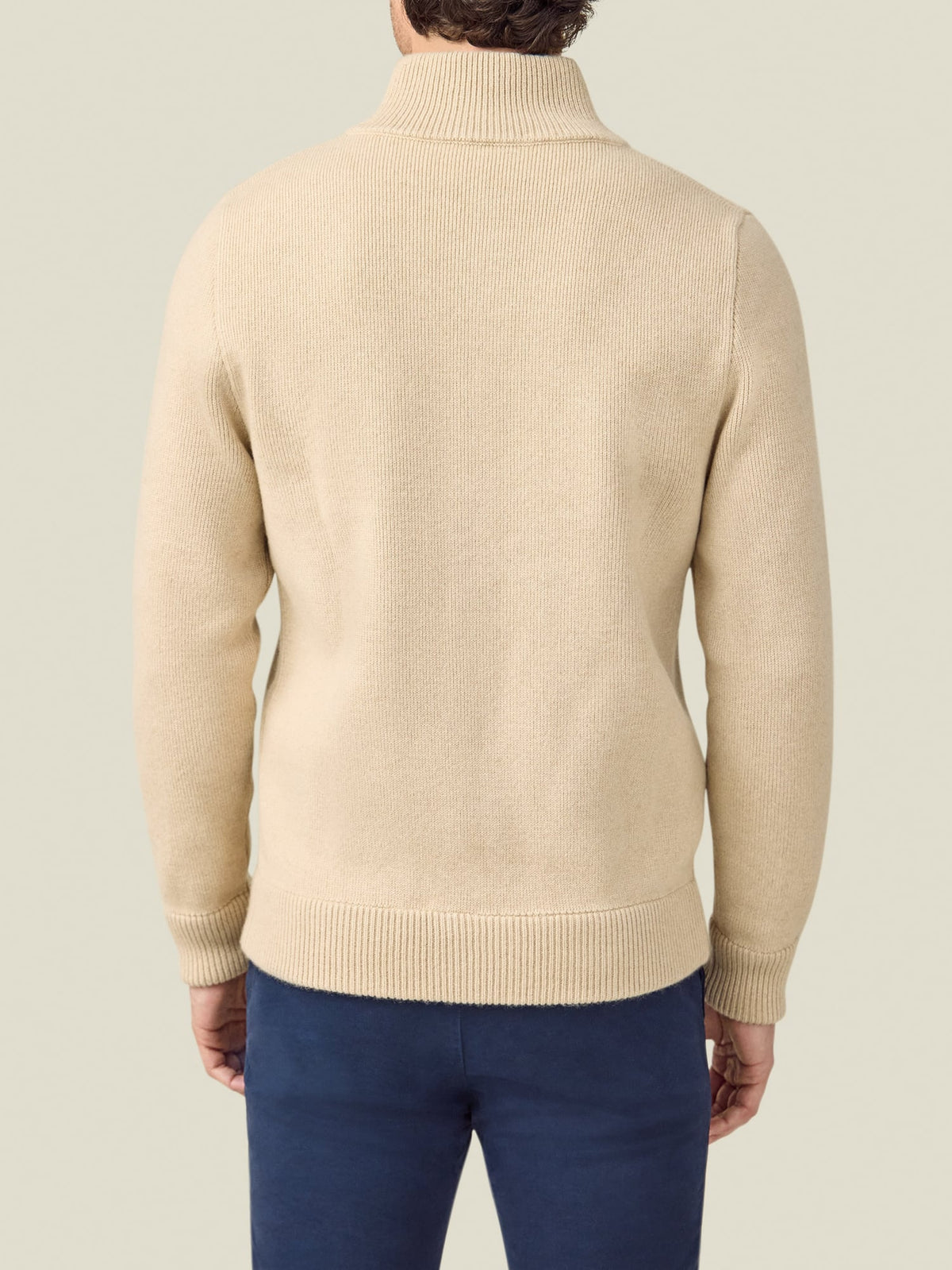 A back view of a model wearing the Luca Faloni Cashmere Bomber in Oatmeal with blue trousers.