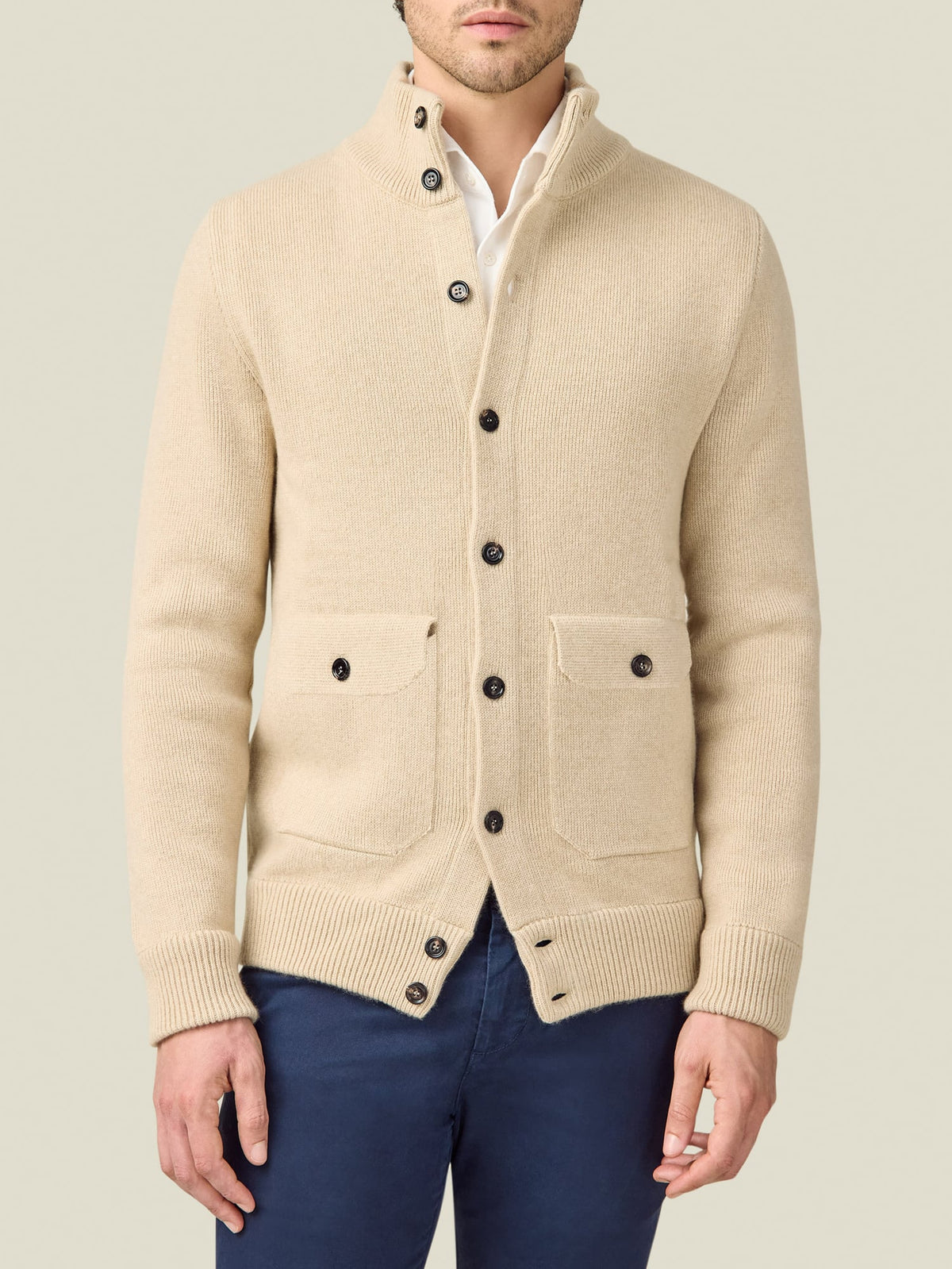 A front view of a model wearing the Luca Faloni Cashmere Bomber in Oatmeal with a white shirt and blue trousers.