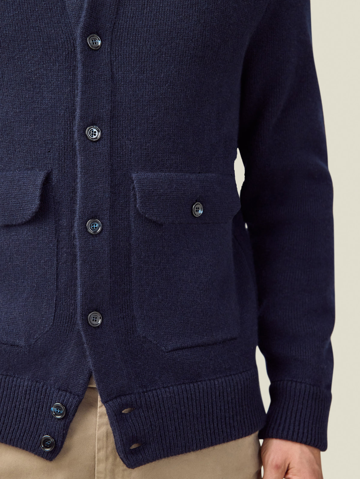 A detail shot of the Midnight Blue Cashmere Bomber, focusing on the chunky knit texture, horn buttons and flap pockets.