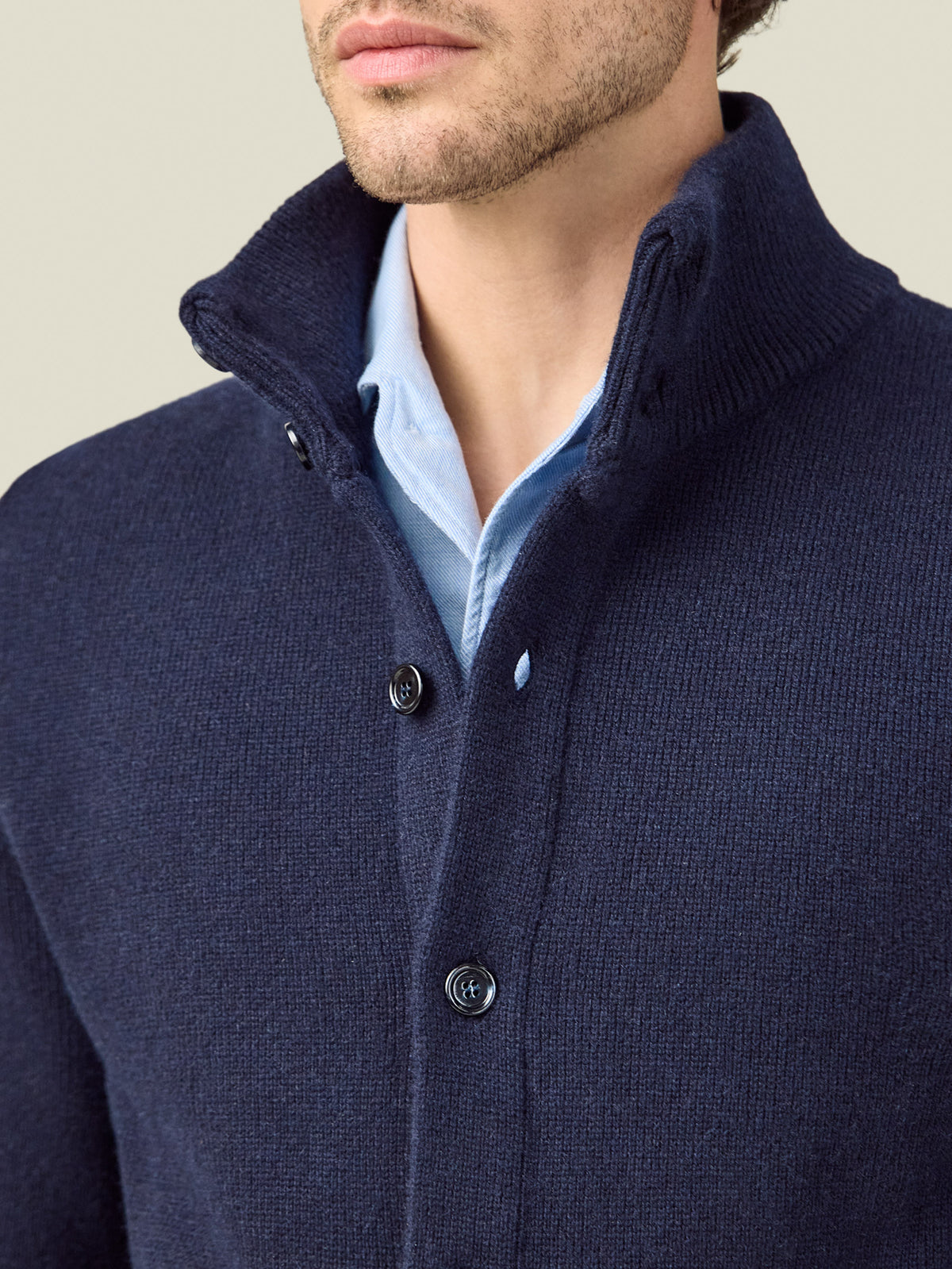 Close-up of the Midnight Blue Cashmere Bomber's ribbed funnel collar and horn buttons, worn over a light blue shirt.